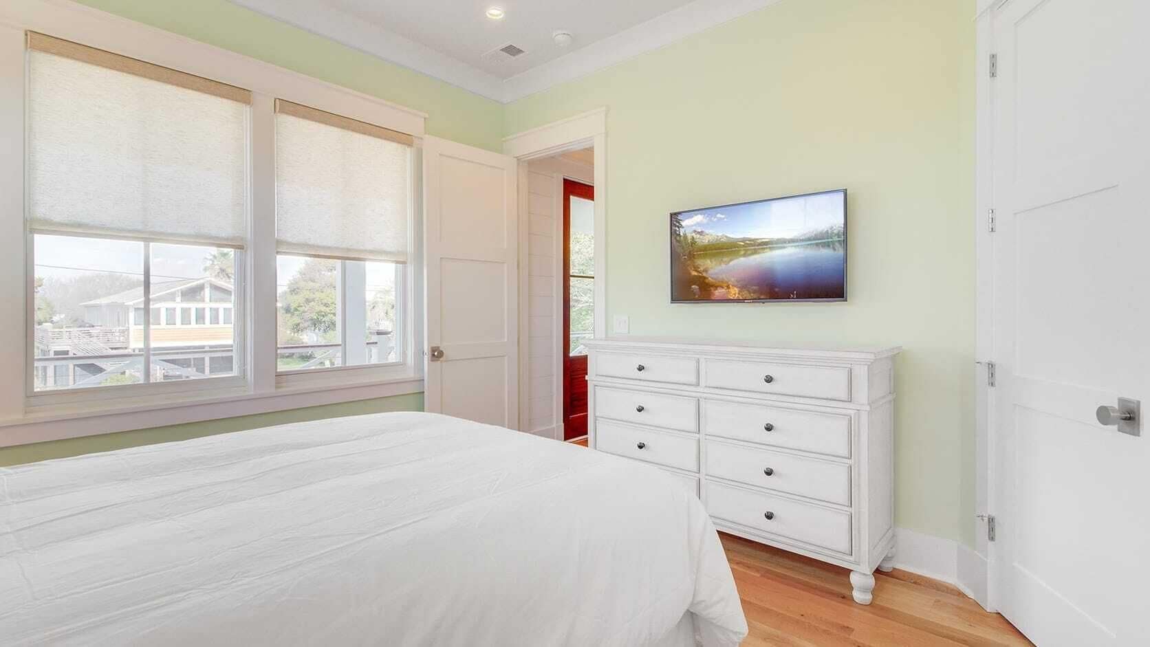A bedroom with a large bed, a white dresser, and a painting on the wall.