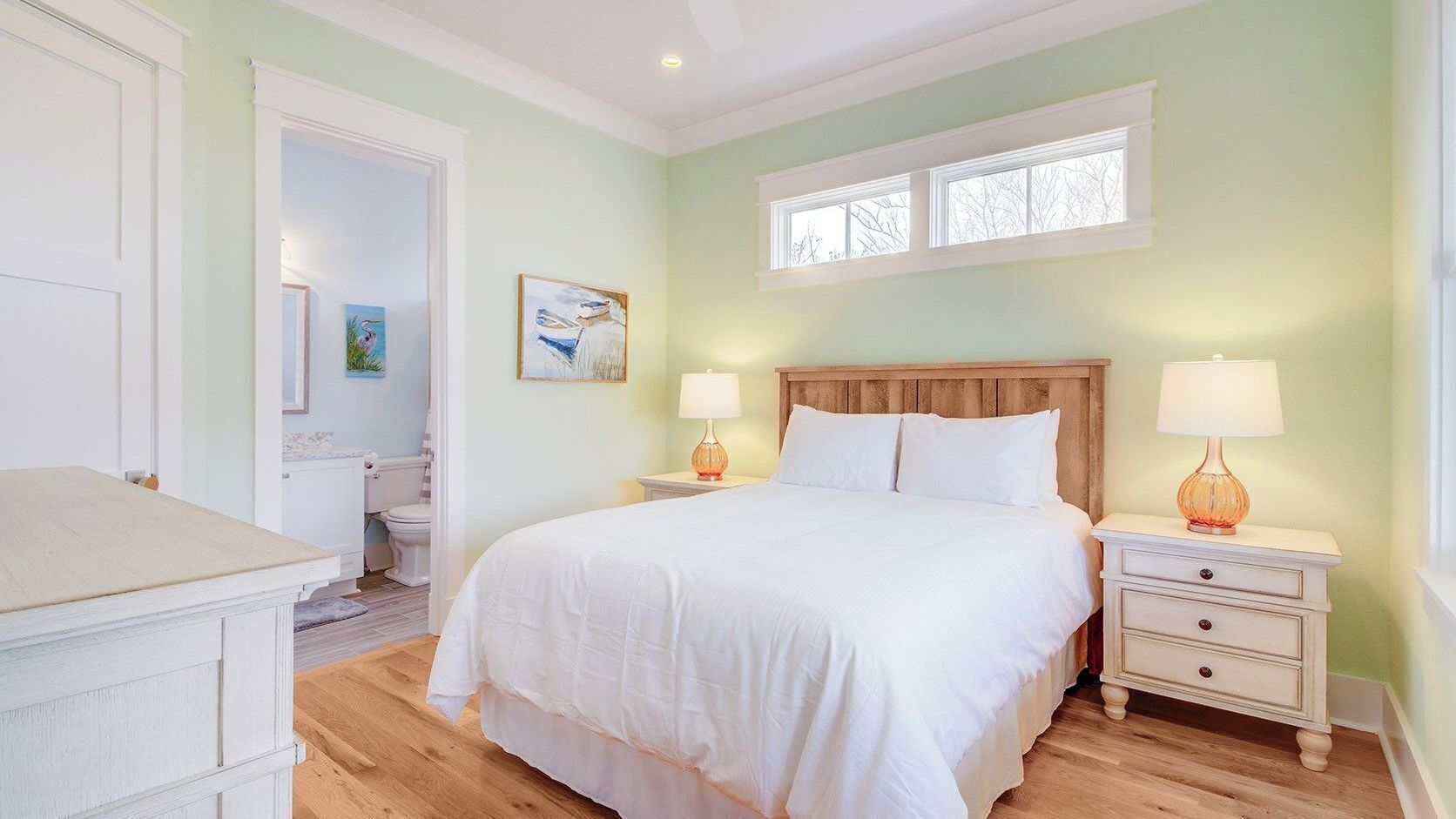 A bedroom with a bed, bedside tables, a window, and a door.