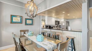 A modern kitchen with white cabinets, stainless steel appliances, and a bar area.