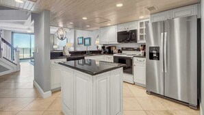 A spacious kitchen with white cabinetry, stainless steel appliances, and a large island.