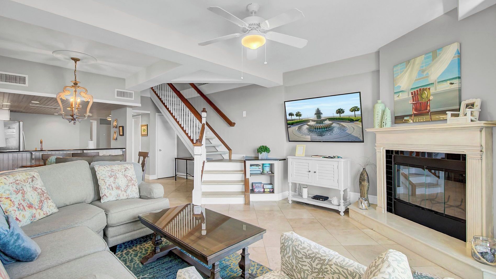 A spacious living room with a sofa, coffee table, fireplace, TV, and a staircase leading to an upper level.