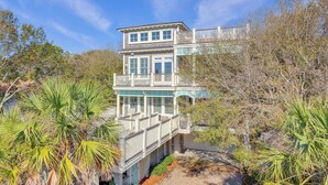 A multi-story house with a balcony, surrounded by trees and a pathway. - 913 Carolina Boulevard by Avantstay Private Pool, Ocean View, Rooftop (Isle of Palms)