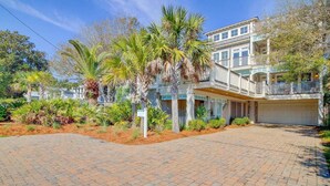 A two-story house with a covered porch and a garage. - 913 Carolina Boulevard by Avantstay Private Pool, Ocean View, Rooftop (Isle of Palms)