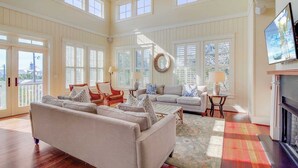 A spacious living room with high ceilings, large windows, and a fireplace. - 913 Carolina Boulevard by Avantstay Private Pool, Ocean View, Rooftop (Isle of Palms)
