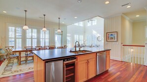 A spacious kitchen with a central island, wooden cabinetry, and pendant lighting. - 913 Carolina Boulevard by Avantstay Private Pool, Ocean View, Rooftop (Isle of Palms)