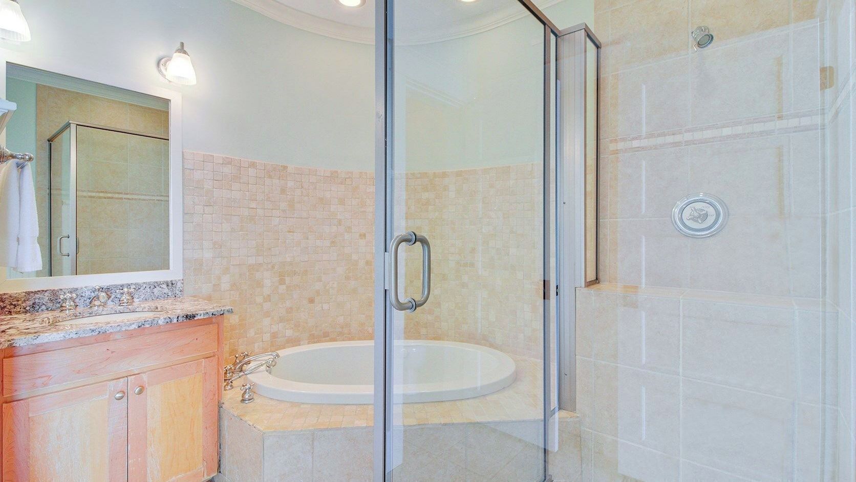 Un baño con ducha de vidrio, lavamanos y espejo.