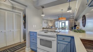 A kitchen with a stove, oven, and blue cabinets. - 11B Mariners Walk by Avantstay Direct Beach Access! Views Communal Pool (Isle of Palms)