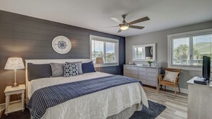 A bedroom with a bed, bedside table, lamp, dresser, chair, and a ceiling fan. - 11B Mariners Walk by Avantstay Direct Beach Access! Views Communal Pool (Isle of Palms)
