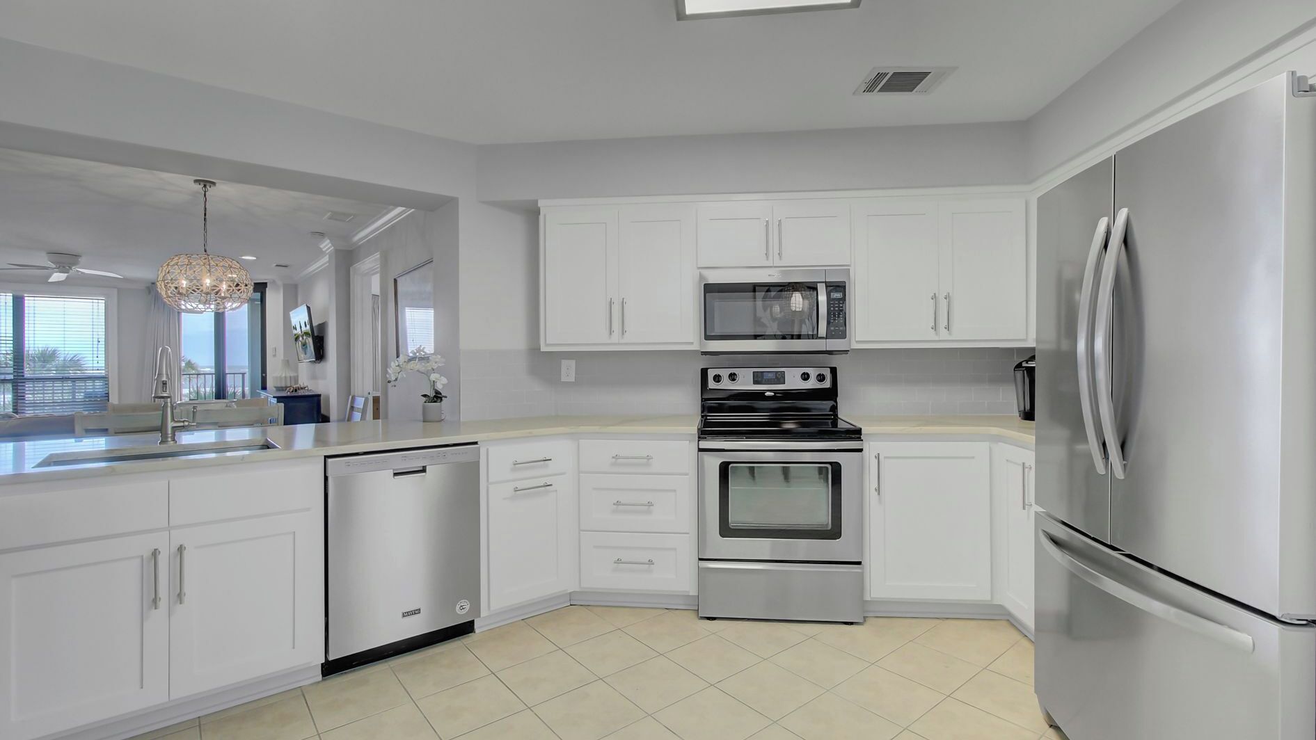 A modern kitchen with white cabinetry, a dishwasher, a double oven, a microwave, and a refrigerator.