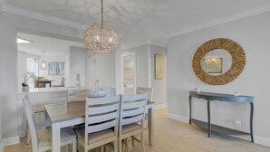 A modern dining area with a central island, a chandelier, and a decorative mirror. - 207 Summerhouse by Avantstay Beachfront Community w/ Ocean Views! (Isle of Palms)