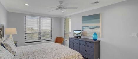 A bedroom with a bed, a dresser, a chair, and a ceiling fan.