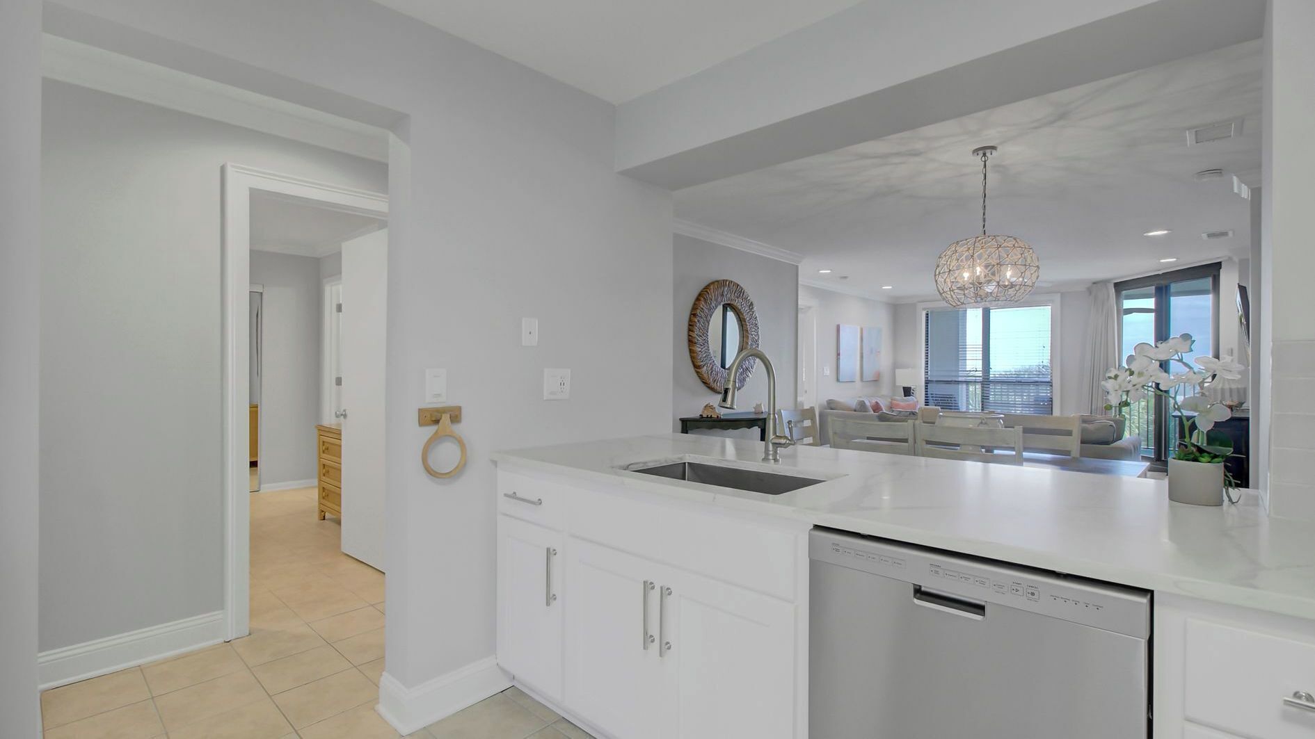 A modern kitchen with white cabinetry, a dishwasher, and a large island with a sink.