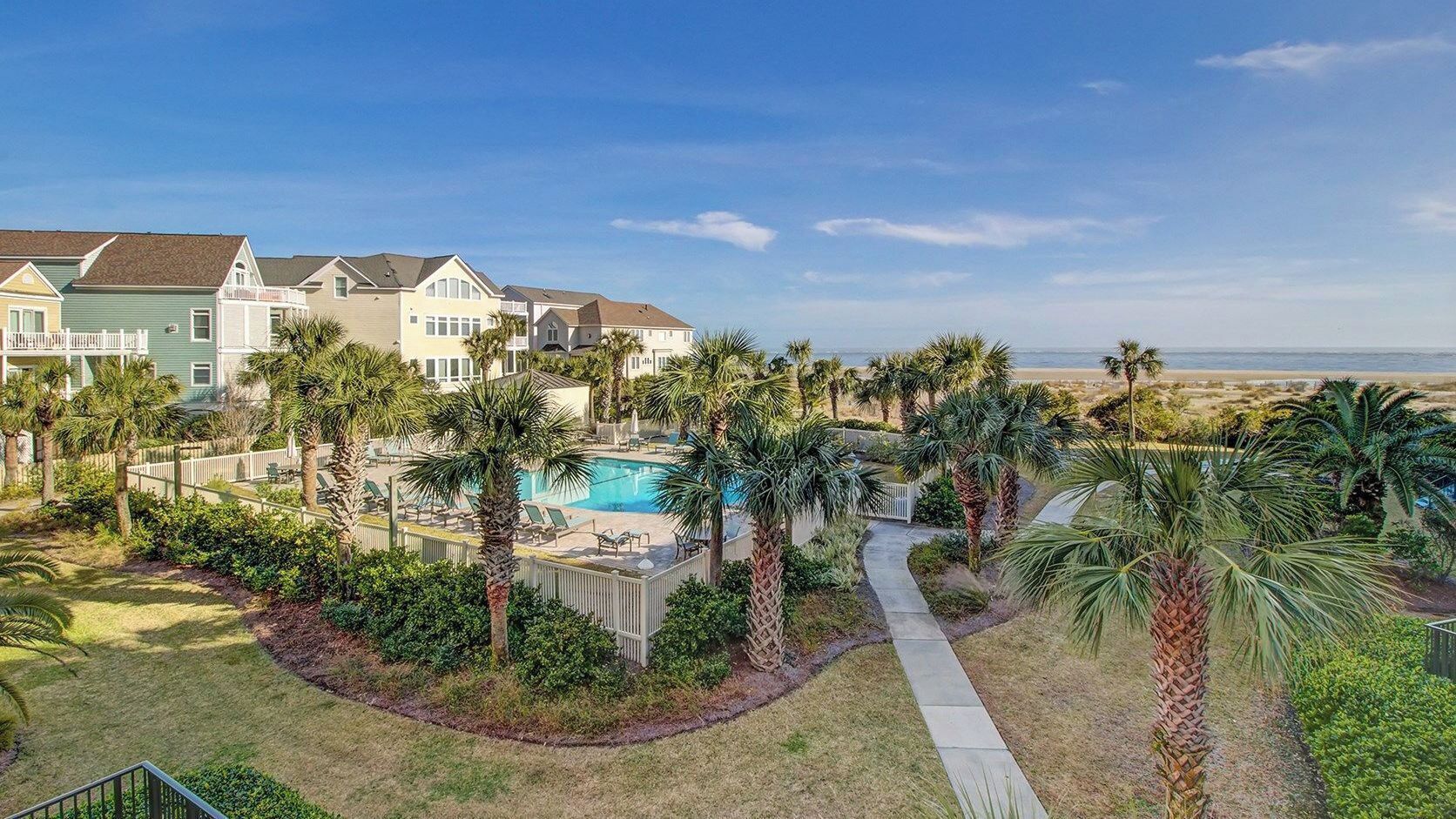 A residential area with a swimming pool, palm trees, and houses.