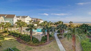 A residential area with a swimming pool surrounded by palm trees and a pathway leading to a gated entrance. - 207 Summerhouse by Avantstay Beachfront Community w/ Ocean Views! (Isle of Palms)