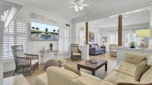 A spacious living room with a large TV, comfortable seating, and a decorative wall.