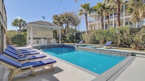 A pool area with lounge chairs, a gazebo, and a building with balconies. - 3001 Palm Boulevard by Avantstay Across From Beach & Ocean Views! (Isle of Palms)