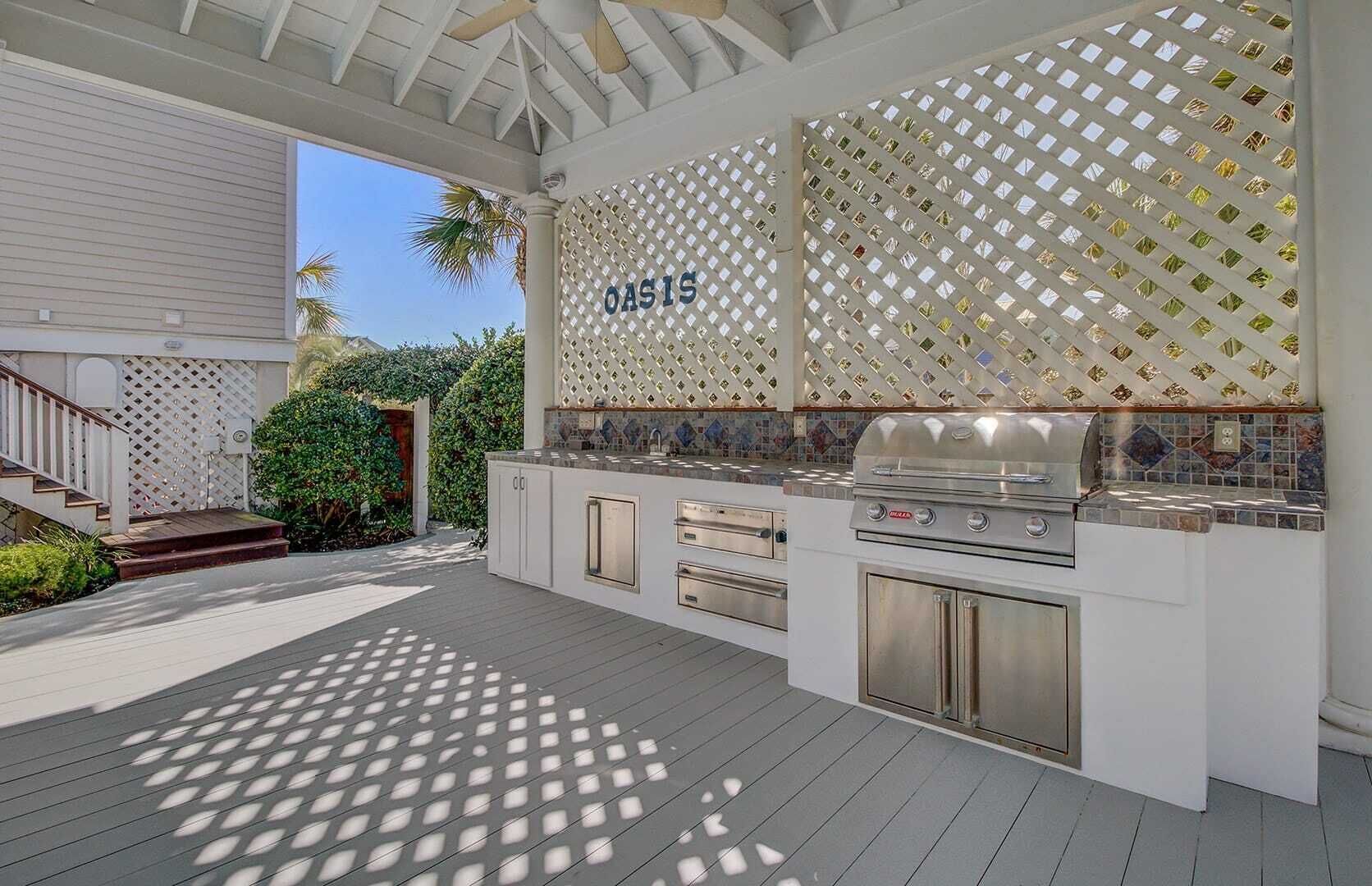 Une cuisine extérieure équipée d’un barbecue, d’un four encastré et d’un mur décoratif orné d’un motif en treillis.