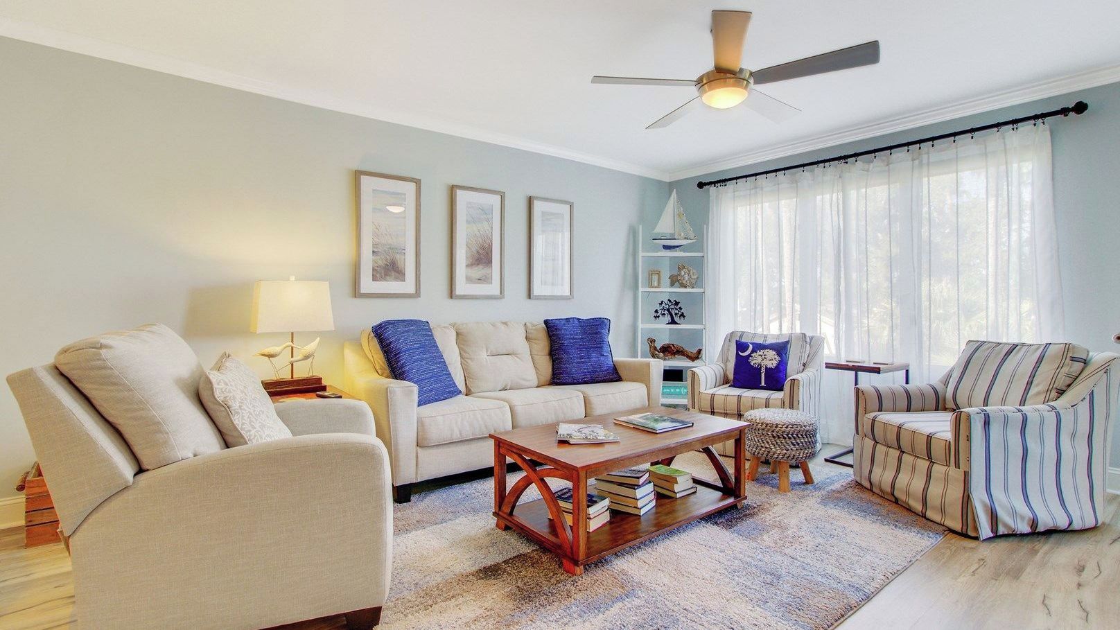 A living room with a sofa, armchairs, a coffee table, and a ceiling fan.