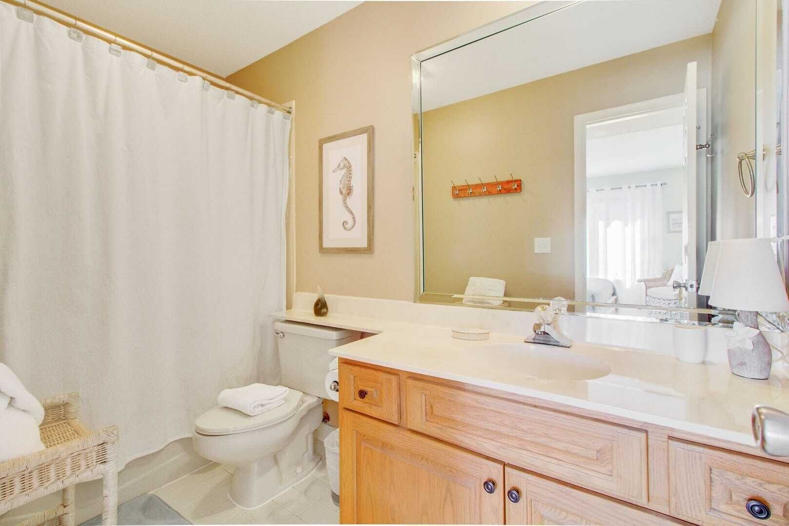 A bathroom with a toilet, a sink, a mirror, and a shower curtain.