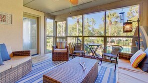 A sunroom with wicker furniture, large windows, and a ceiling fan. - 405 Yacht Harbor by Avantstay Marina Views + Pool Access + Outdoor Lounge Near Golf & Beach (Isle of Palms)