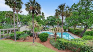 A pool surrounded by palm trees and lush greenery, with a gazebo and lounge chairs in the background. - 405 Yacht Harbor by Avantstay Marina Views + Pool Access + Outdoor Lounge Near Golf & Beach (Isle of Palms)