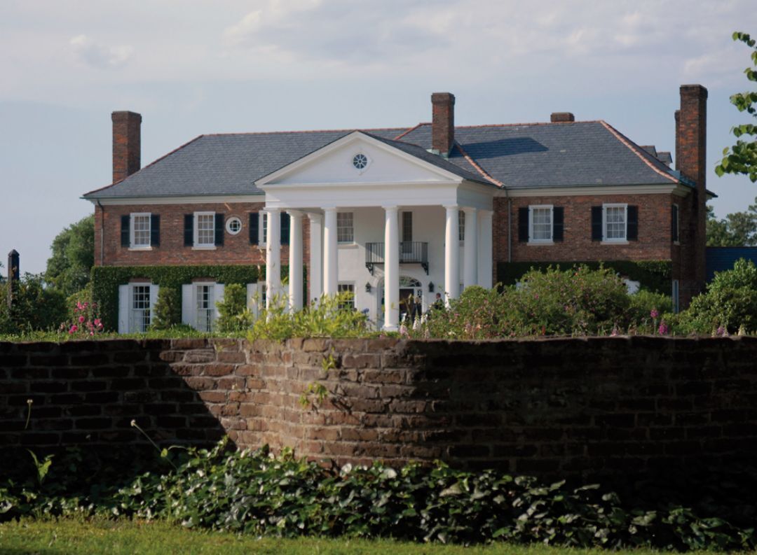 A large brick house with a central porch and multiple chimneys.