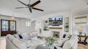 A spacious living room with a fireplace, comfortable seating, and a ceiling fan.