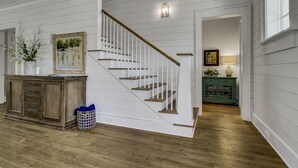A staircase with white railings and wooden steps, a wooden cabinet with drawers, a wicker basket, and a painting on the wall.
