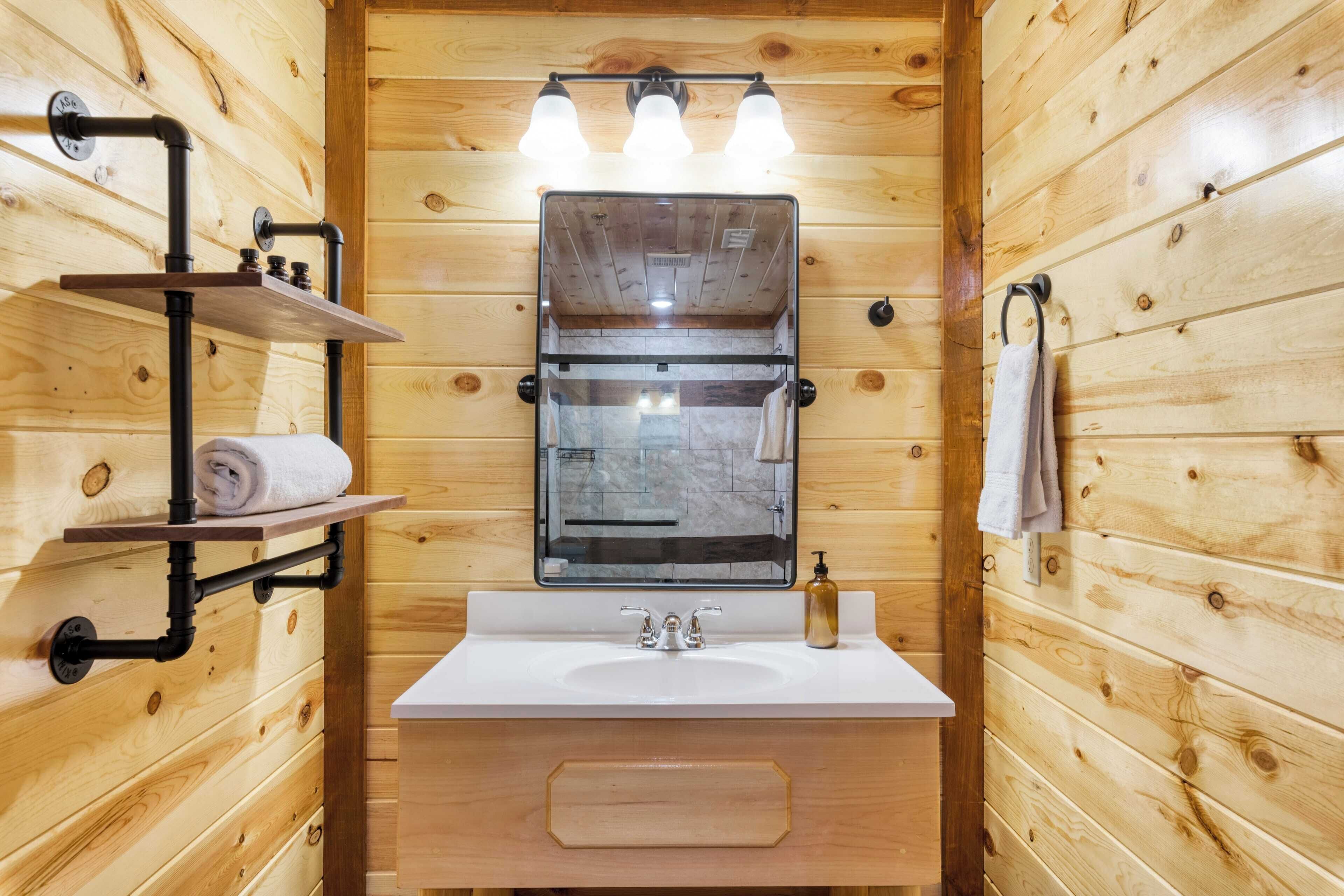 Un baño rústico con cabaña, que incluye un lavamanos blanco, un espejo y un perchero para toallas.
