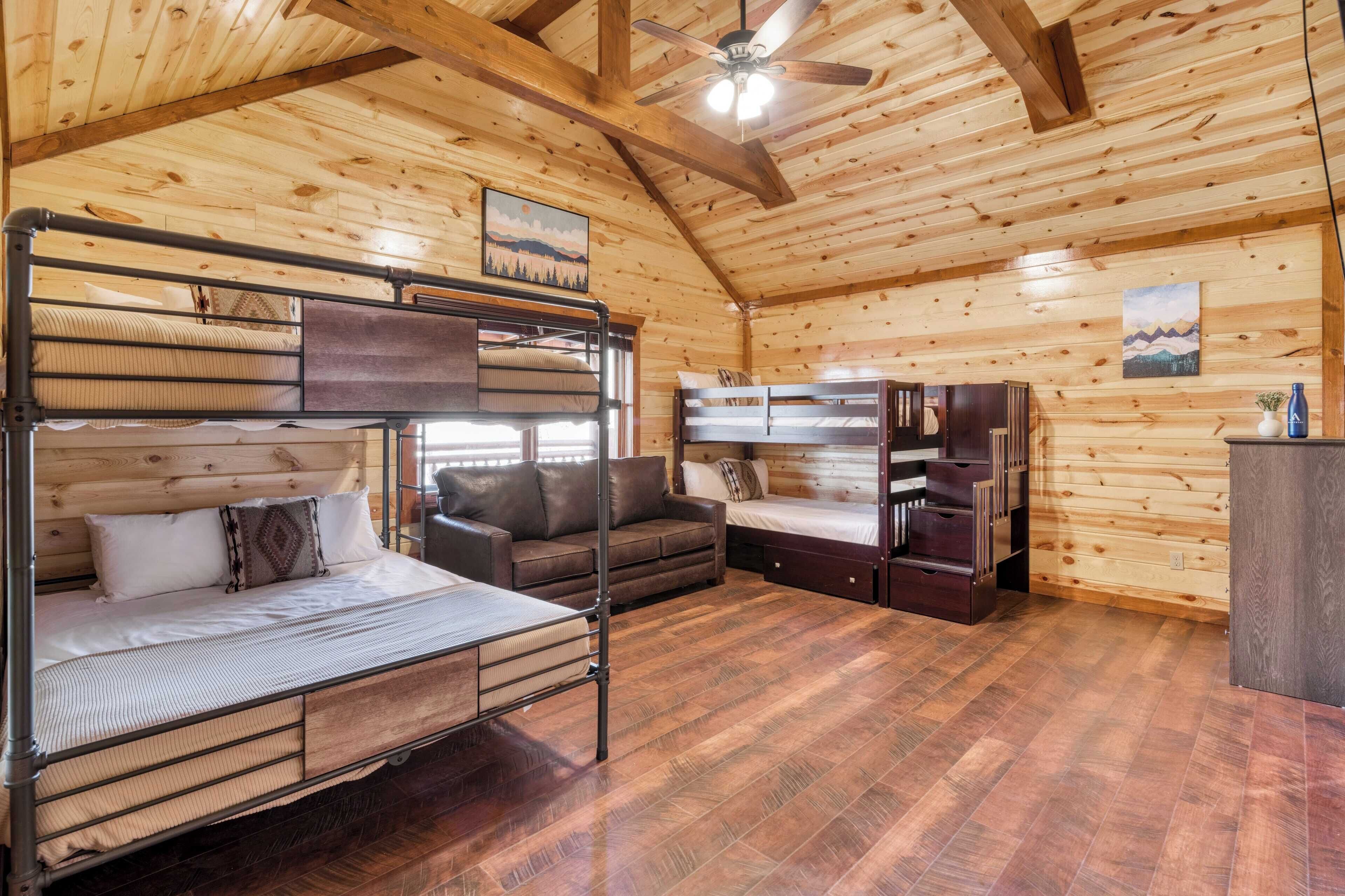 A wooden cabin interior with bunk beds, a sofa, and a desk.