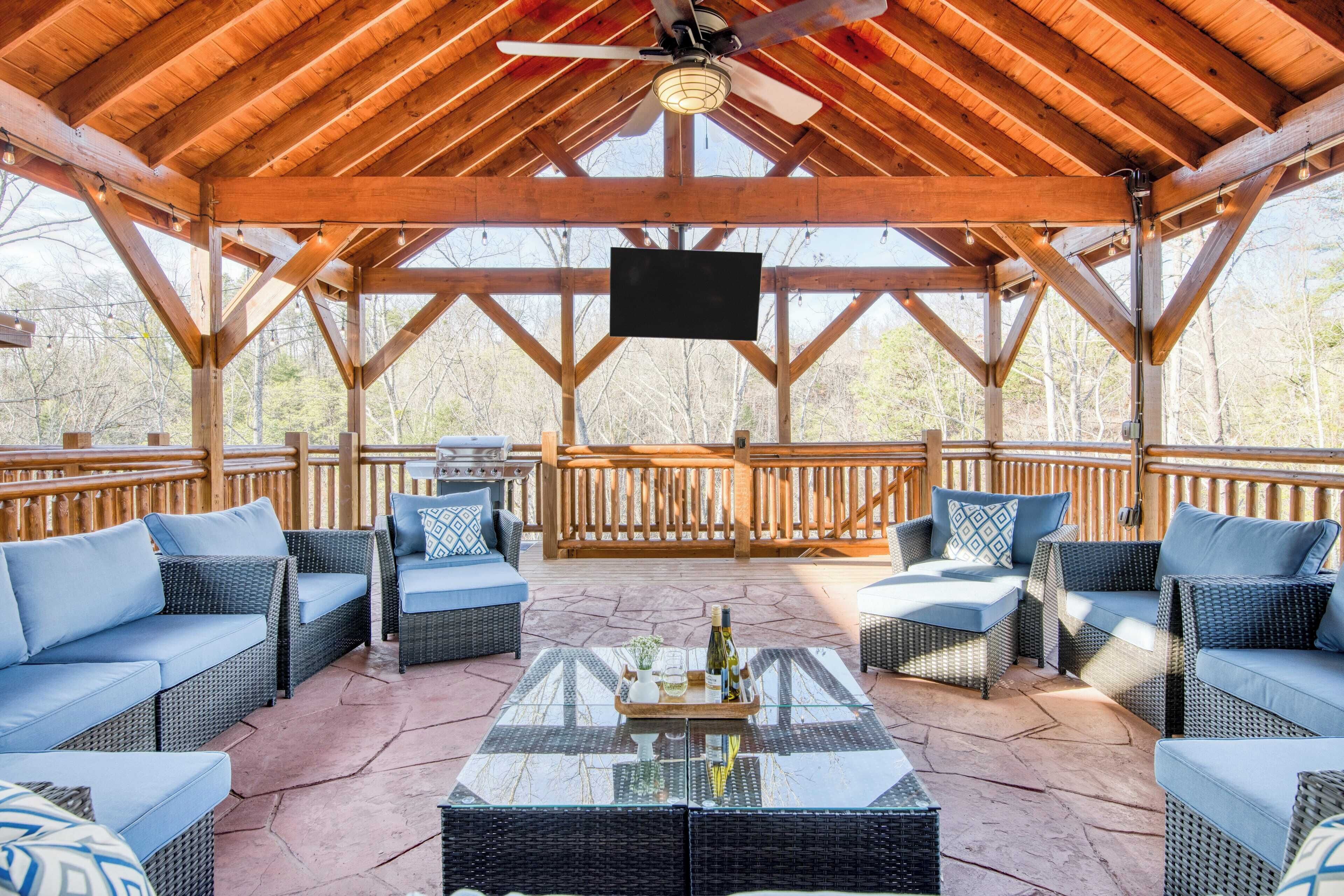 A covered outdoor seating area with wicker furniture and a central glass table.