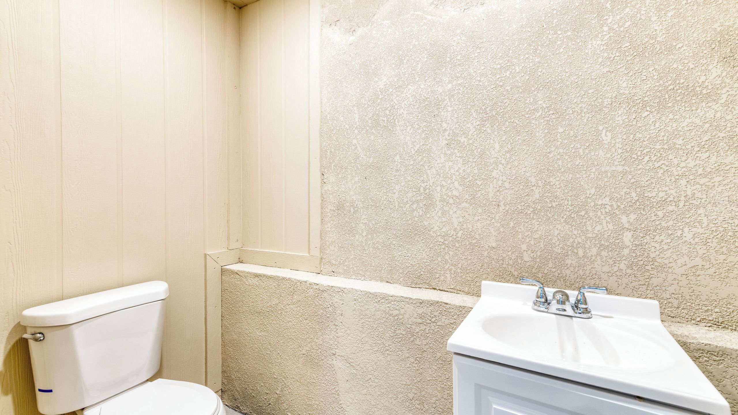 Ein Badezimmer mit Toilette, Waschbecken und rauen Wänden.