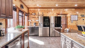 A modern kitchen with stainless steel appliances, wooden paneling, and a granite countertop. - Boon by Avantstay 40-guest Luxe Smokies Retreat (Sevierville)