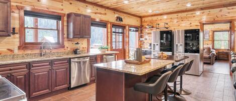 A modern kitchen with wooden paneling, stainless steel appliances, and a central island with bar stools.