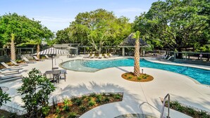 A pool area with lounge chairs, a palm tree, and a gazebo. - 1403 Ocean Club by Avantstay Beach Home w/ Great Kitchen (Isle of Palms)
