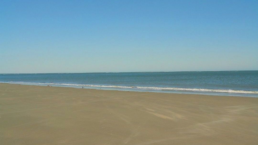 A beach with a clear sky and calm sea.