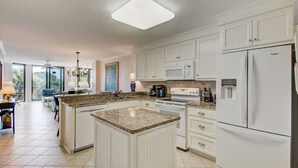 A modern kitchen with white cabinetry, a granite countertop, and a built-in oven. - 216 C Shipwatch by Avantstay Shared Pool + Ocean Views + Walk to the Beach (Isle of Palms)