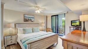 A bedroom with a wooden bed, two bedside tables with lamps, a ceiling fan, a TV, and a sliding glass door to a balcony. - 216 C Shipwatch by Avantstay Shared Pool + Ocean Views + Walk to the Beach (Isle of Palms)