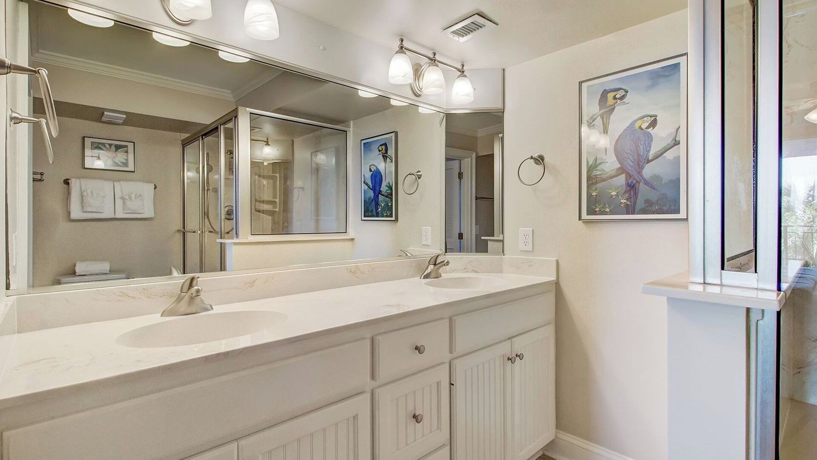 Une salle de bain avec deux lavabos, un grand miroir et des œuvres d’art accrochées au mur.