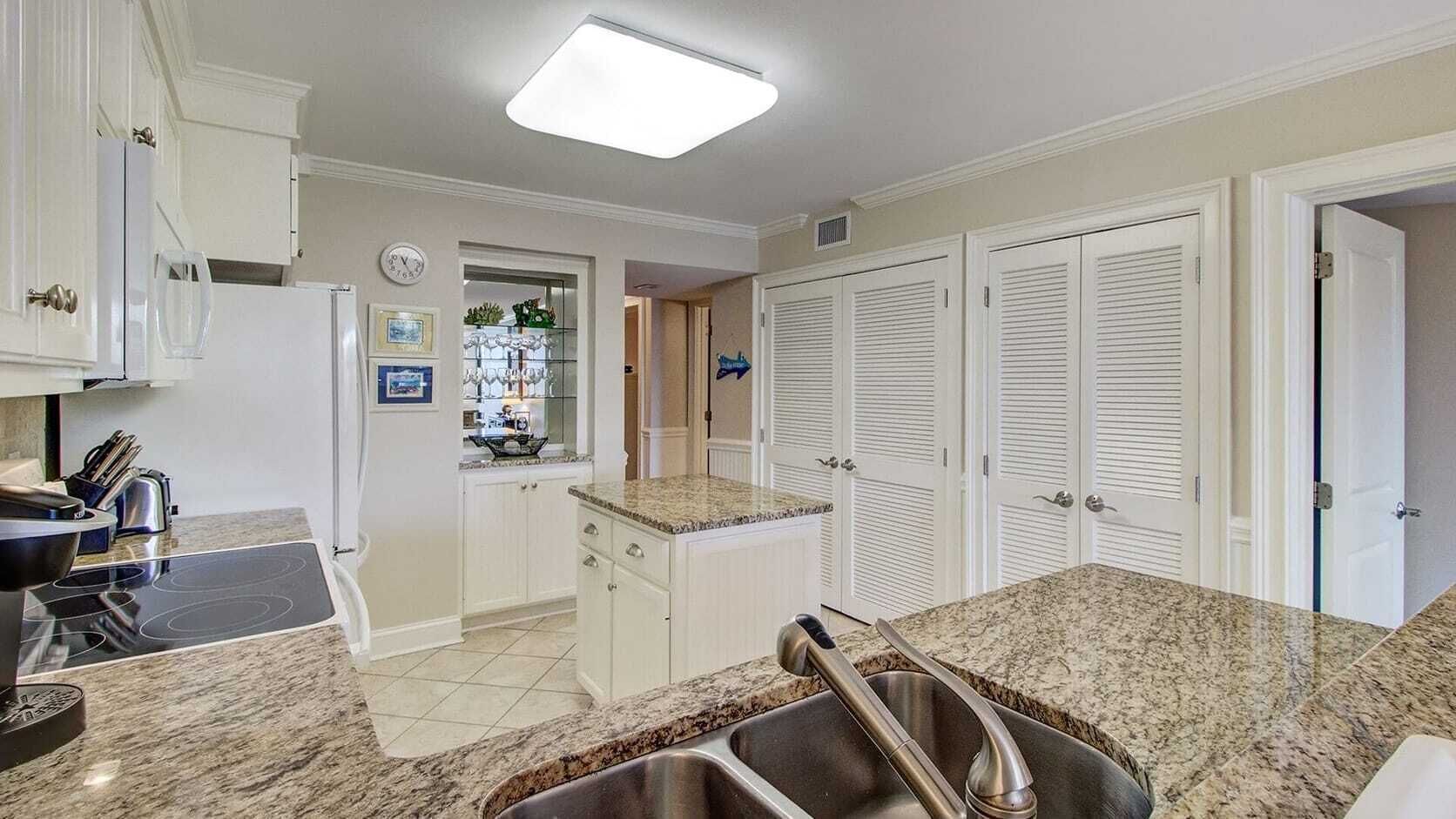 A kitchen with white cabinets, a granite countertop, a stainless steel sink, and a built-in oven.
