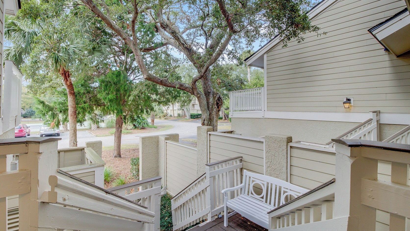 A residential property with a staircase, white railings, and a tree in the background.