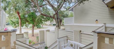 A residential property with a staircase, white railings, and a tree in the background.