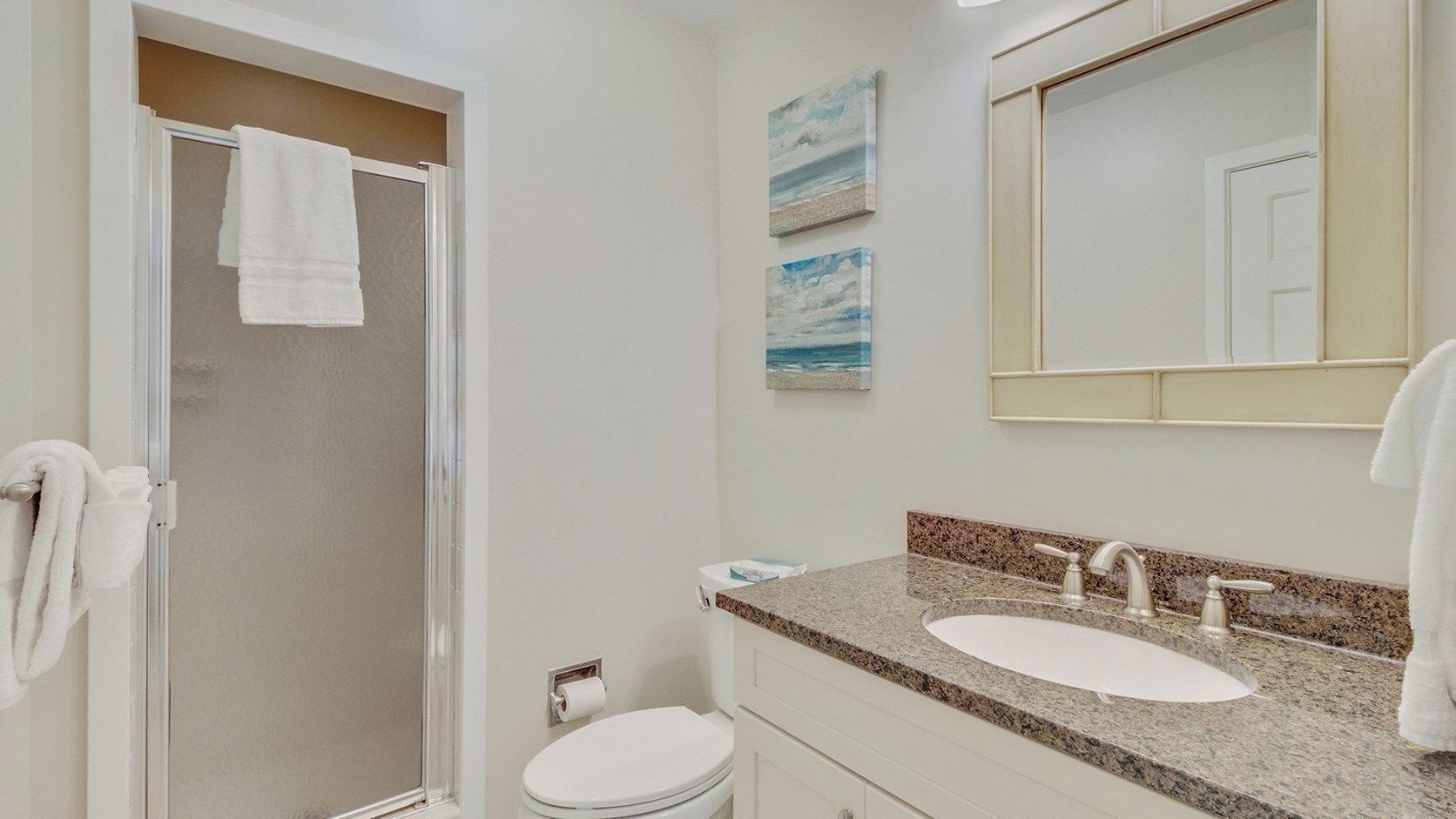 Un baño con ducha, inodoro, lavabo y espejo.