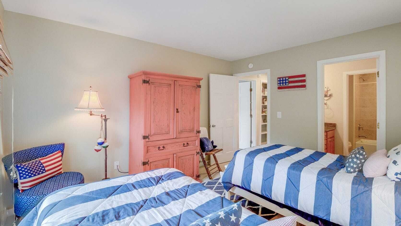 A bedroom with two beds, a wardrobe, a lamp, and an American flag decoration.