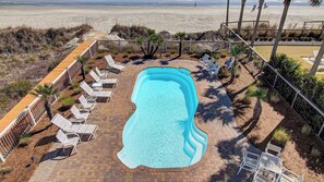 A swimming pool with lounge chairs and a wooden deck. - 502 Ocean Blvd by Avantstay Beachfront w/ Pool & Ocean Views! (Isle of Palms)