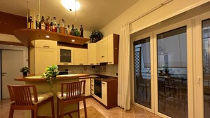 Una cocina moderna con barra, comedor y puerta corrediza de vidrio que da a un balcón exterior.