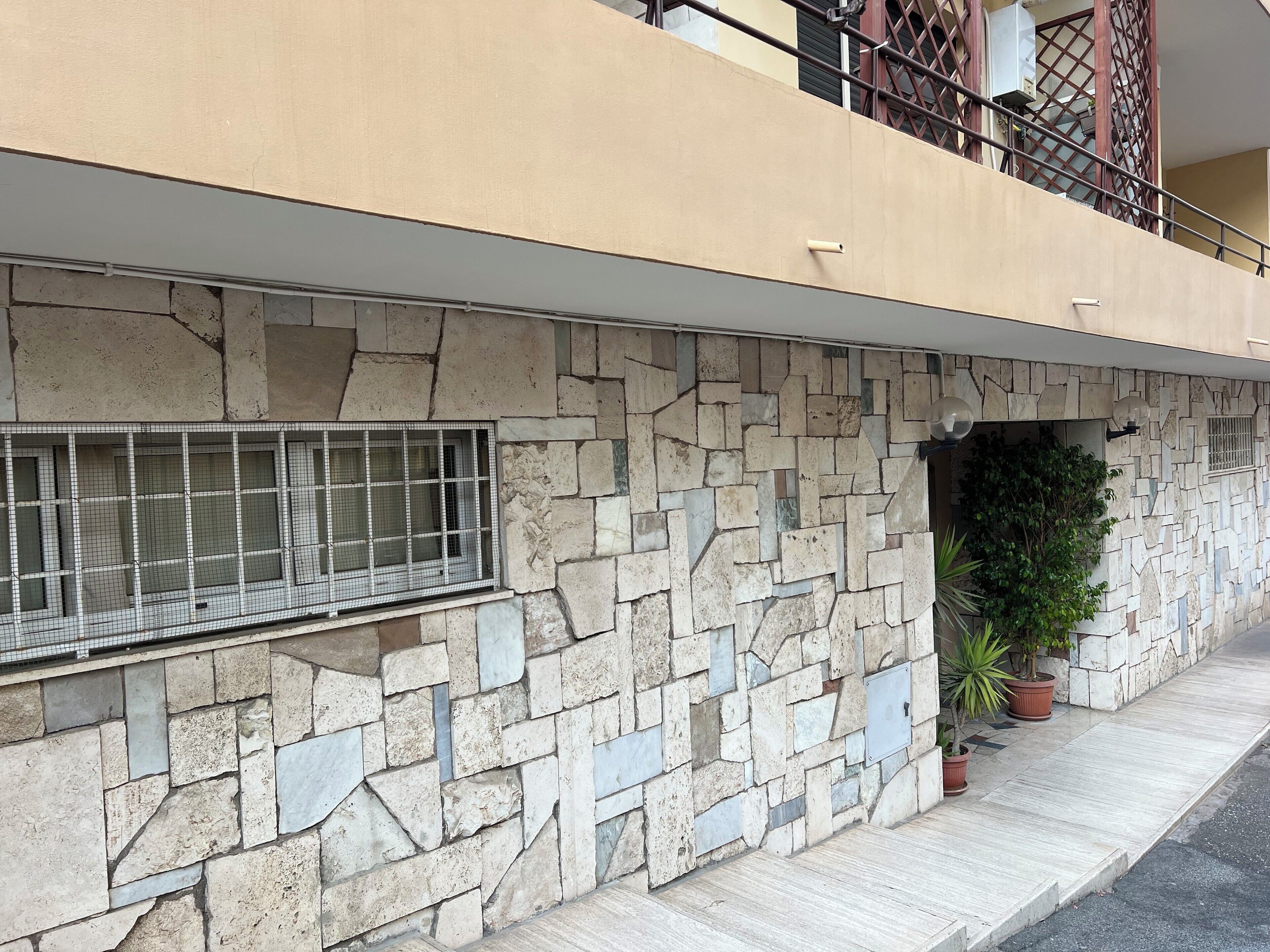A stone facade with a window and a potted plant.