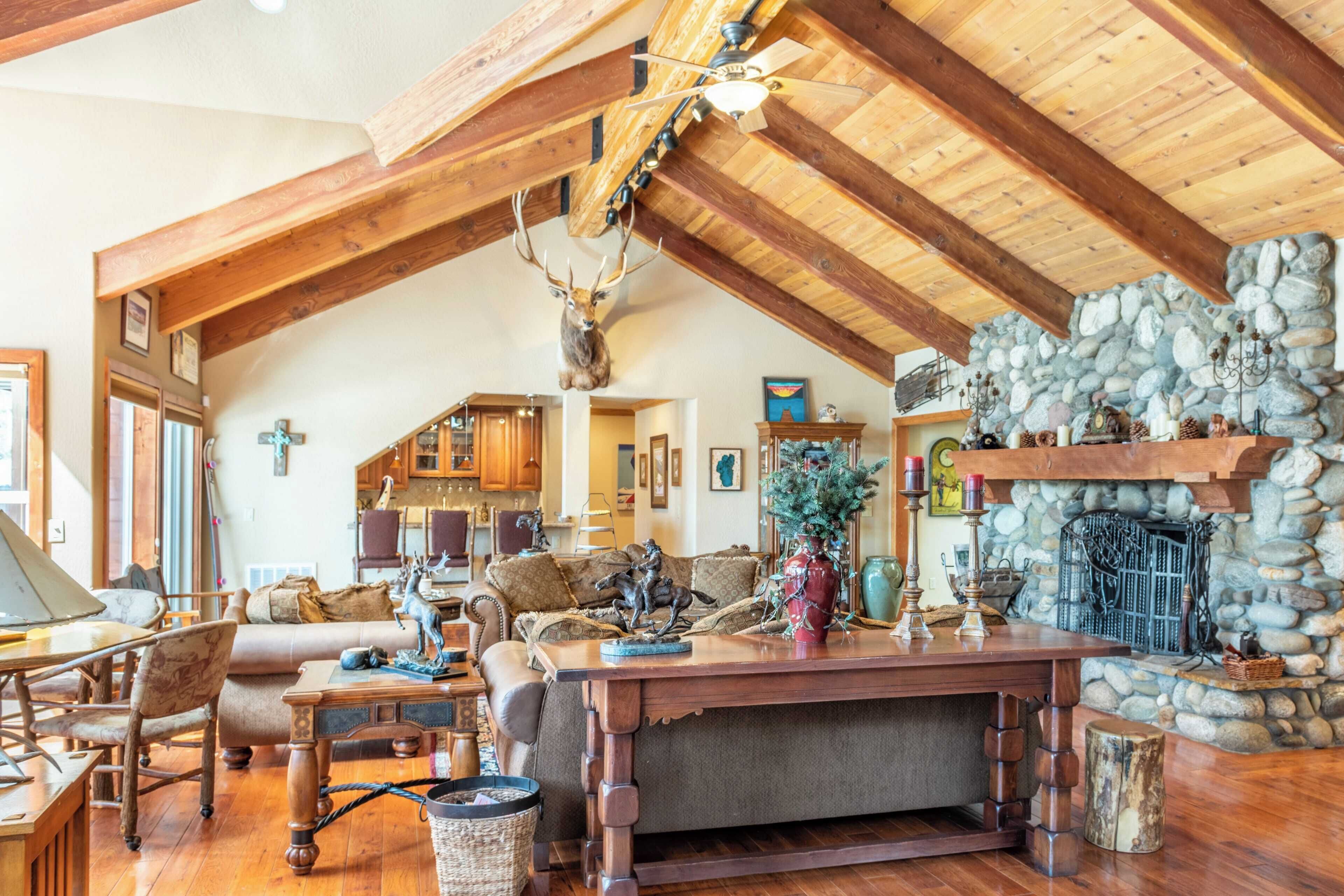 A rustic interior with wooden beams, a stone fireplace, and a dining area with a wooden table and chairs.