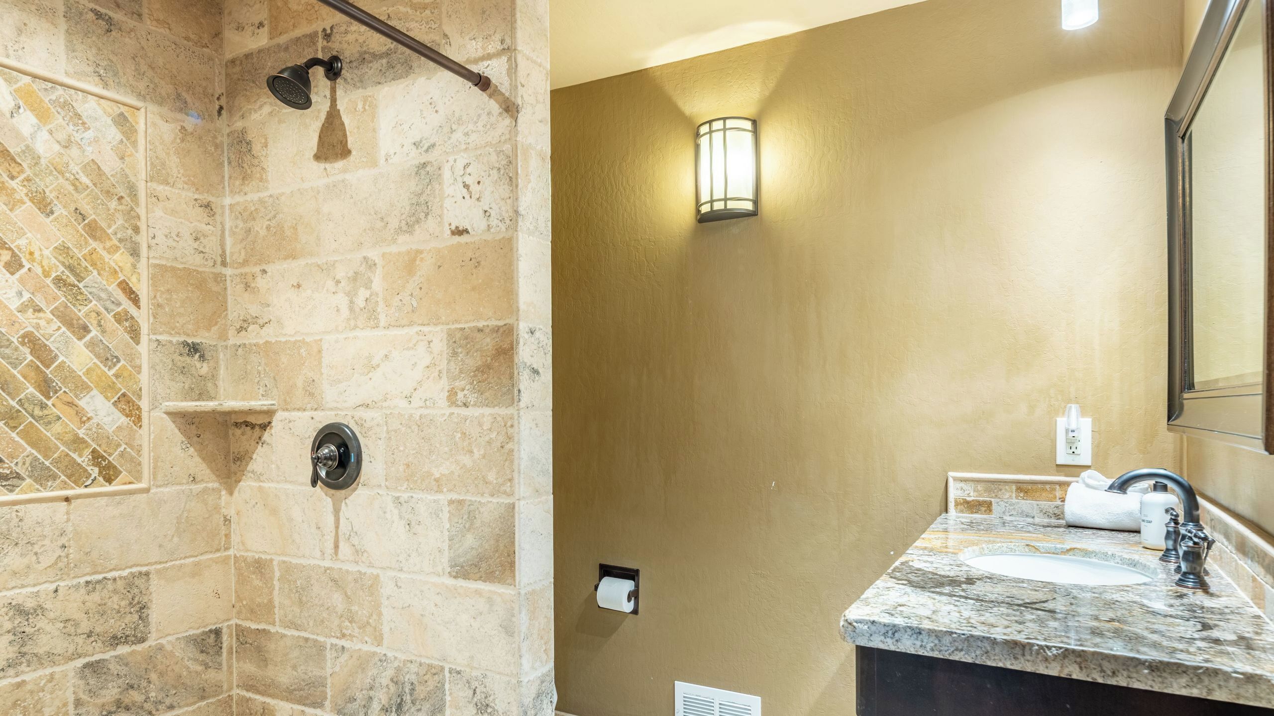 Une salle de bain avec une douche, un lavabo, une serviette et un miroir.