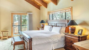 Une chambre à coucher avec un grand lit, deux tables de chevet avec des lampes, un banc et une commode.